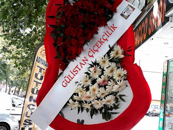 Kırmızı güllerle çevrelenmiş kalp biçimli çelenk, kaldırımda