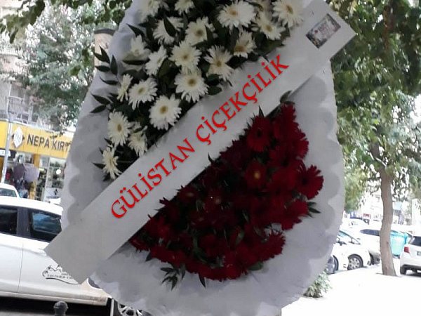 Beyaz ve kırmızı çiçekli ayaklı çelenk, teslim için kaldırıma çıkarılmış